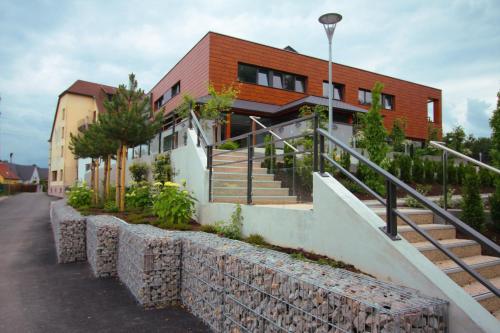 a house with a stone wall next to a building at Hôtel Restaurant Les Alizés in Lipsheim