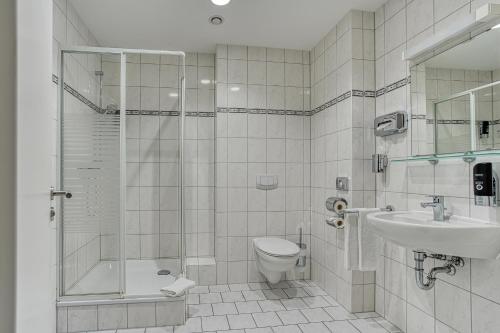 a bathroom with a shower and a toilet and a sink at Centro Hotel Celler Tor in Braunschweig