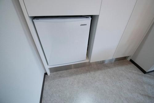 a small white refrigerator in a corner of a room at UCHI Living Stay KCU in Sapporo