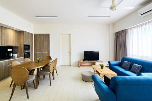 a living room with a blue couch and a table at By The Sea Beach Front Apartment in Batu Ferringhi