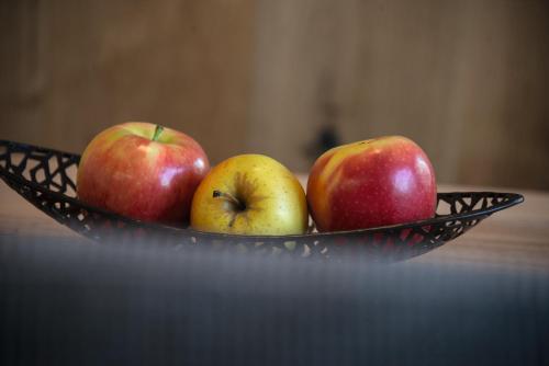 three apples in a black bowl on a table at Appartements Bergheim St Andrä bei Brixen in Bressanone