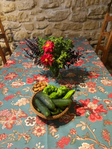 a table with a basket of vegetables and a vase of flowers at Solano de Moran in Murillo de Gállego