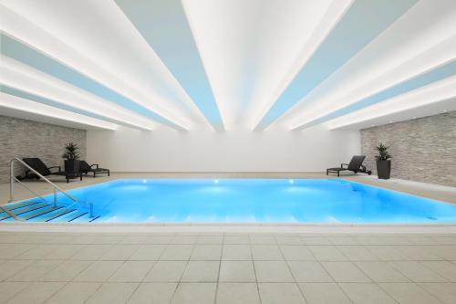 duży basen z niebieską wodą w budynku w obiekcie Sporthotel Fuchsbachtal w mieście Barsinghausen