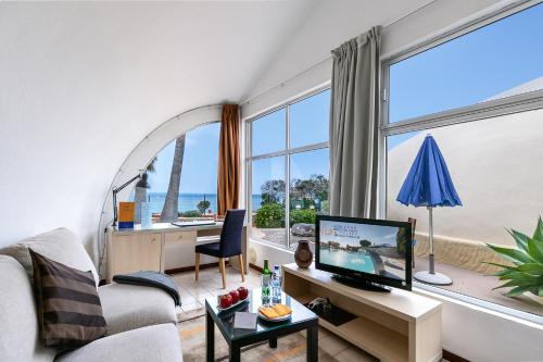 a living room with a couch and a desk with a television at Hotel LIVVO Risco del Gato Suites in Costa Calma