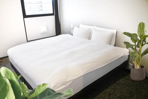 a white bed with a white comforter on top of it at A Good Day Fukuoka Riverside in Fukuoka