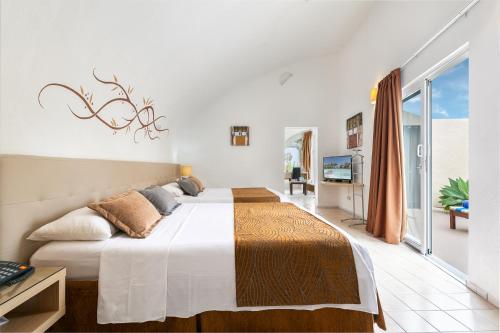 sypialnia z 2 łóżkami i balkonem w obiekcie Hotel LIVVO Risco del Gato Suites w mieście Costa Calma