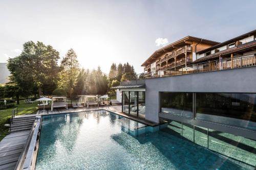 a swimming pool in front of a house at Parkhotel Holzerhof in Maranza