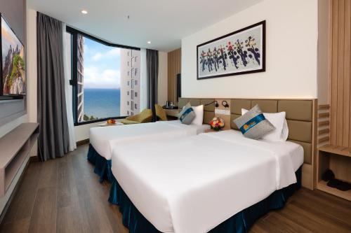 two beds in a hotel room with a large window at Lucky Sun Hotel Nha Trang Beach in Nha Trang