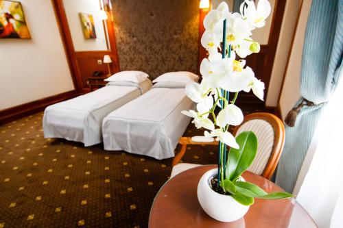 a hotel room with two beds and a vase of flowers at Hotel Select in Iaşi
