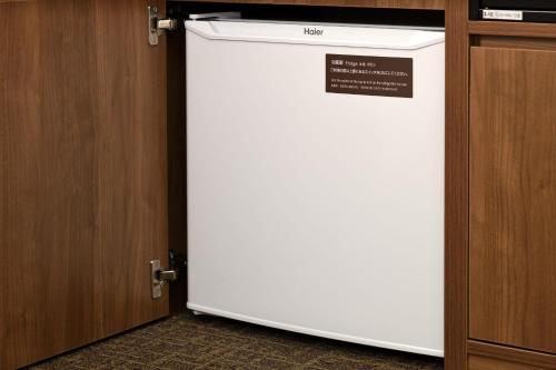 a white refrigerator sitting inside of a cabinet at Dormy Inn Kawasaki Natural Hot Spring in Kawasaki