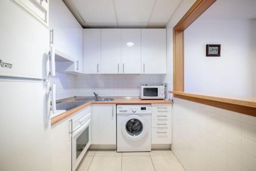 a kitchen with a washing machine and a microwave at Primera Planta Punta Umbria 2 dormitorios junto al mar (1) in Punta Umbría