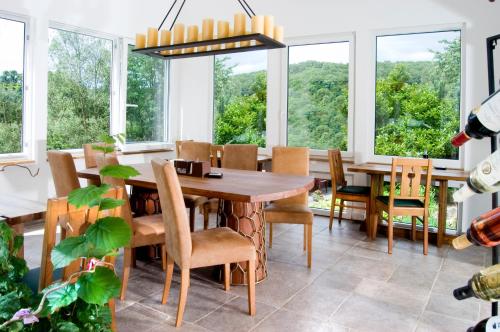 jadalnia z drewnianym stołem i krzesłami oraz dużymi oknami w obiekcie Hotel An der Sauer w mieście Minden