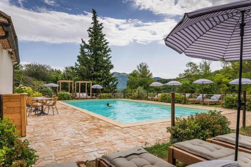 a swimming pool with chairs and an umbrella at Borgo Castello Panicaglia in Nocera Umbra