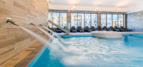 a swimming pool with chairs in a building at Apartament Siesta Sunny Spa in Kołobrzeg