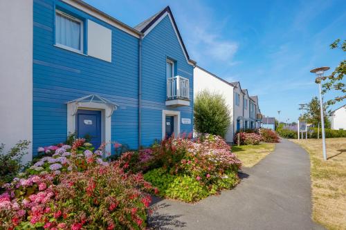 Un bâtiment bleu avec des fleurs devant lui dans l'établissement Pierre & Vacances Résidence Le Chant des Oiseaux, à Courseulles-sur-Mer