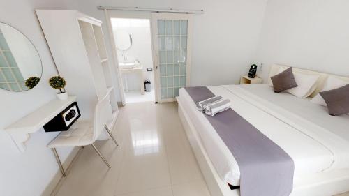 a white bedroom with a large bed and a mirror at Casa Blanca Gili Air in Gili Air