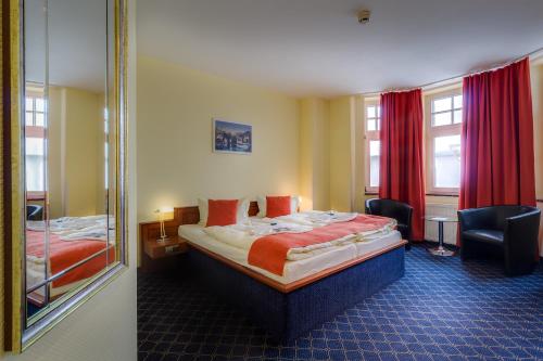 ein Hotelzimmer mit einem Bett und einem Spiegel in der Unterkunft Hotel Deutsches Haus Mittweida in Mittweida