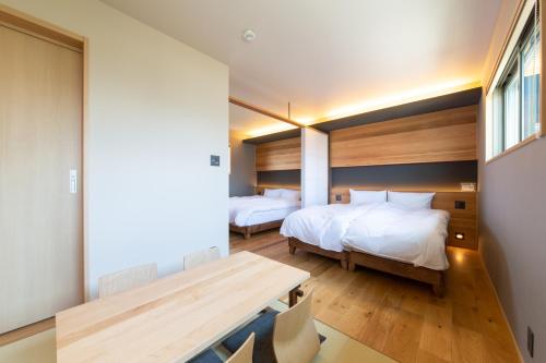 a bedroom with two beds and a wooden table at KIKI HOTEL in Kanazawa