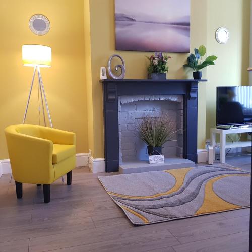 a living room with a yellow chair and a fireplace at Hollis House - 5 Bedroom Contractor Accommodation in Derby in Derby