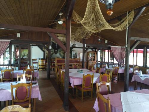 un restaurante con mesas y sillas y mesas y sillas rosas en Pansion Ribnjak, en Našice