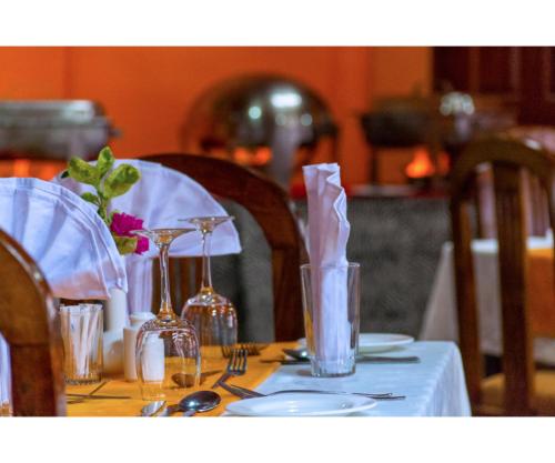 a table with a white table cloth with glasses and plates at Thomsons Falls Lodge in Nyahururu