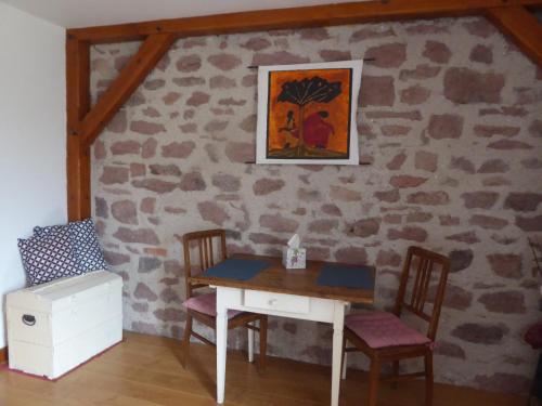 une table et des chaises dans une pièce avec un mur en pierre dans l'établissement La Chambre de Manon, à Saint-Maurice