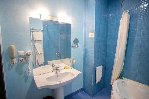 a blue bathroom with a sink and a shower at Gloria Hotel in Tashkent