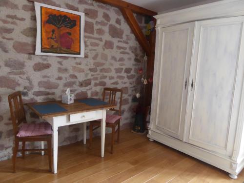 a table and chairs in a room with a stone wall at La Chambre de Manon in Saint-Maurice