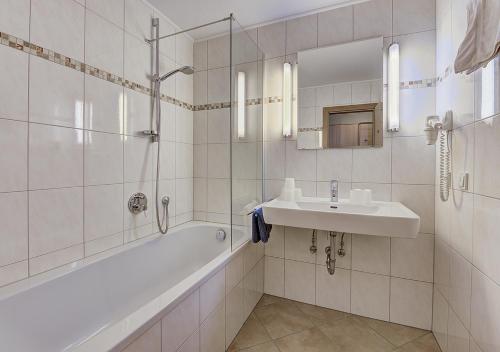 a white bathroom with a sink and a bath tub at Mountainlovers Berghotel SeidlAlm in Saalbach Hinterglemm