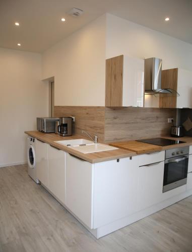 une cuisine avec des armoires blanches, un évier et un lave-vaisselle dans l'établissement La Maison de Jules, à Paray-le-Monial