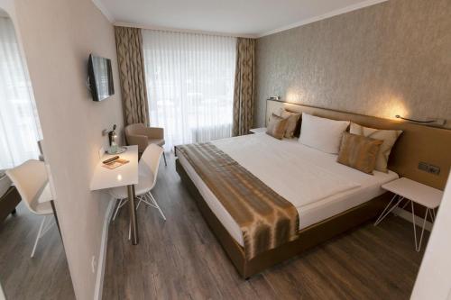 a hotel room with a large bed and a desk at Hotel Prinz Anton in Düsseldorf