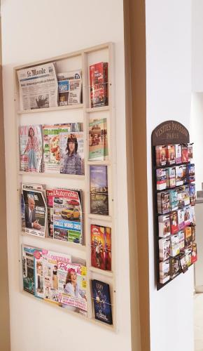 a wall with magazines and newspapers on it at Hôtel Brésil Opéra SPA in Paris