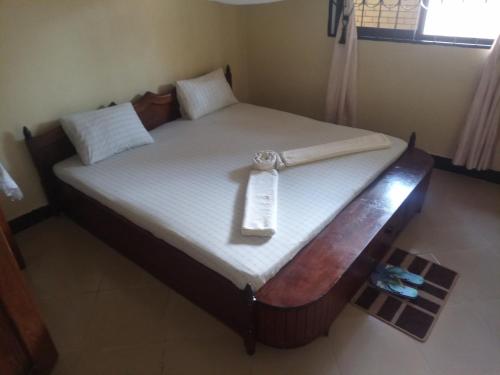 a bed with a wooden frame with a tag on it at Jfour comfort zone hostel in Dar es Salaam