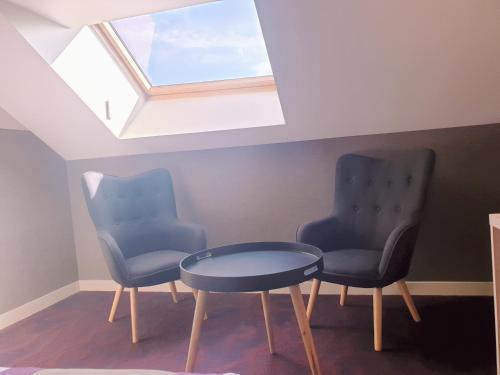 two chairs and a table in a room with a skylight at Hôtel Brésil Opéra SPA in Paris