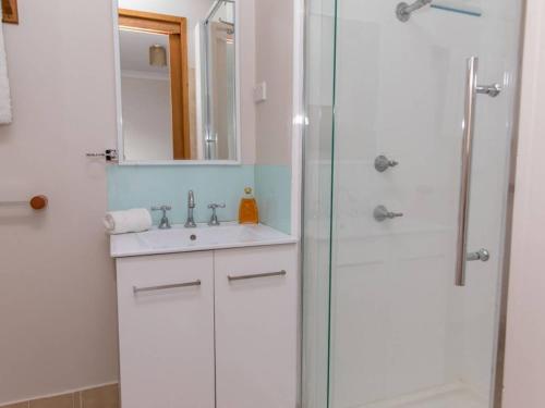 a white bathroom with a shower and a sink at Kookas Nest - waterfront home, tranquil setting in Dunbogan