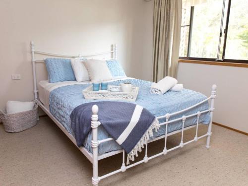 a bedroom with a bed with a blue blanket at Kookas Nest - waterfront home, tranquil setting in Dunbogan