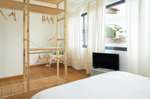um quarto com uma cama e uma televisão num quarto em Hostel da Palmeira em Praia da Vitória