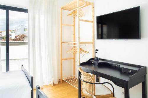 a bedroom with a desk with a television and a bed at Hostel da Palmeira in Praia da Vitória