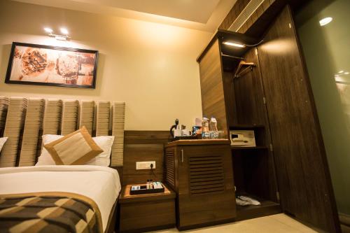 a small hotel room with a bed and a closet at Bizz The Hotel in Rajkot