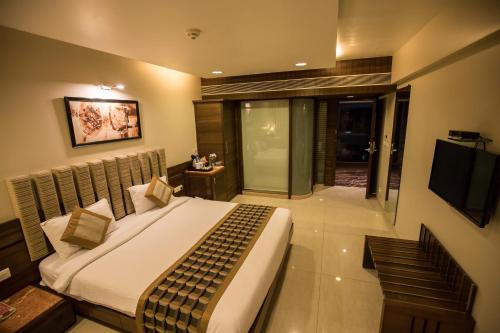 a bedroom with a large bed and a television at Bizz The Hotel in Rajkot