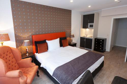 a hotel room with a bed and a chair at Hotel Prinz Anton in Düsseldorf