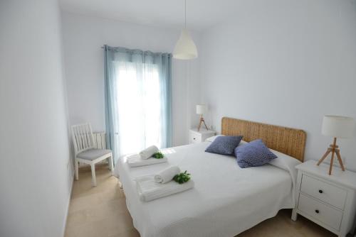 1 dormitorio con cama blanca y almohadas azules en PLAZA ALFONSO SÁNCHEZ FERRAJÓN, en Jerez de la Frontera