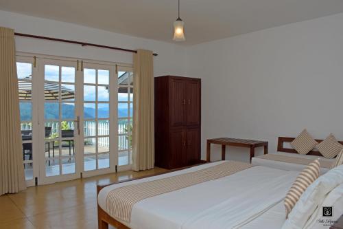 a bedroom with a large bed and a balcony at Villa Perpetua in Bandarawela