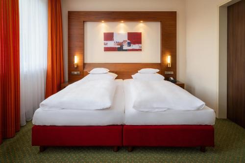 2 Einzelbetten in einem Hotelzimmer mit roten Vorhängen in der Unterkunft Parkhotel am Taunus in Oberursel