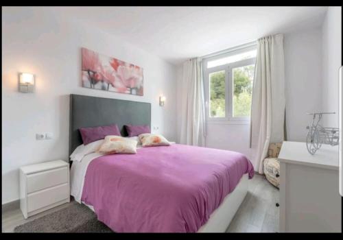 a bedroom with a purple bed and a window at Ronda Playa in Can Picafort