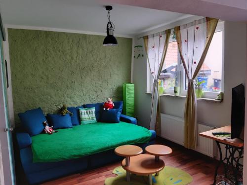 uma sala de estar com um sofá verde e dois bancos em Villa Windschief em Thale