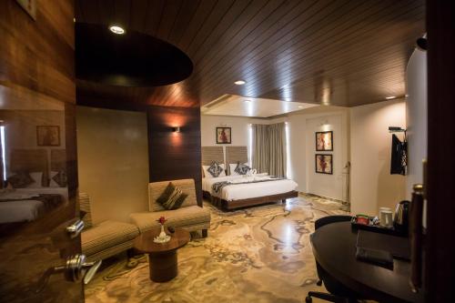 a living room with a bed and a couch and a table at Bizz The Hotel in Rajkot