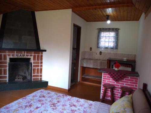 a living room with a brick fireplace and a table at Pousada Borogan in Monte Verde