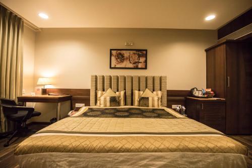 a bedroom with a large bed and a desk at Bizz The Hotel in Rajkot