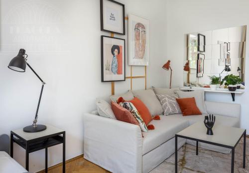 sala de estar con sofá blanco con almohadas de color naranja en Cozy Old Town Apartments, en Cracovia